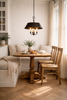 Nestled corner of a home with a solid brass pendant lantern and wooden dining table, chairs, and a bench.