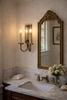 traditional powder bathroom with marble vanity and brass faucet featuring double arm candle wall sconce in warm white interior