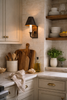 traditional kitchen with marble countertops, open wood shelving, and classic wall sconce lighting