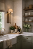 kitchen wall sconce lighting with marble counters, farmhouse sink, green cabinets and brass faucet