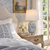 Blue and white ceramic table lamp styled on an antique bedside table in a light-filled traditional bedroom