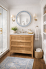 Bathroom with white marble counter wooden, cane vanity, round mirror, and decorative elements.